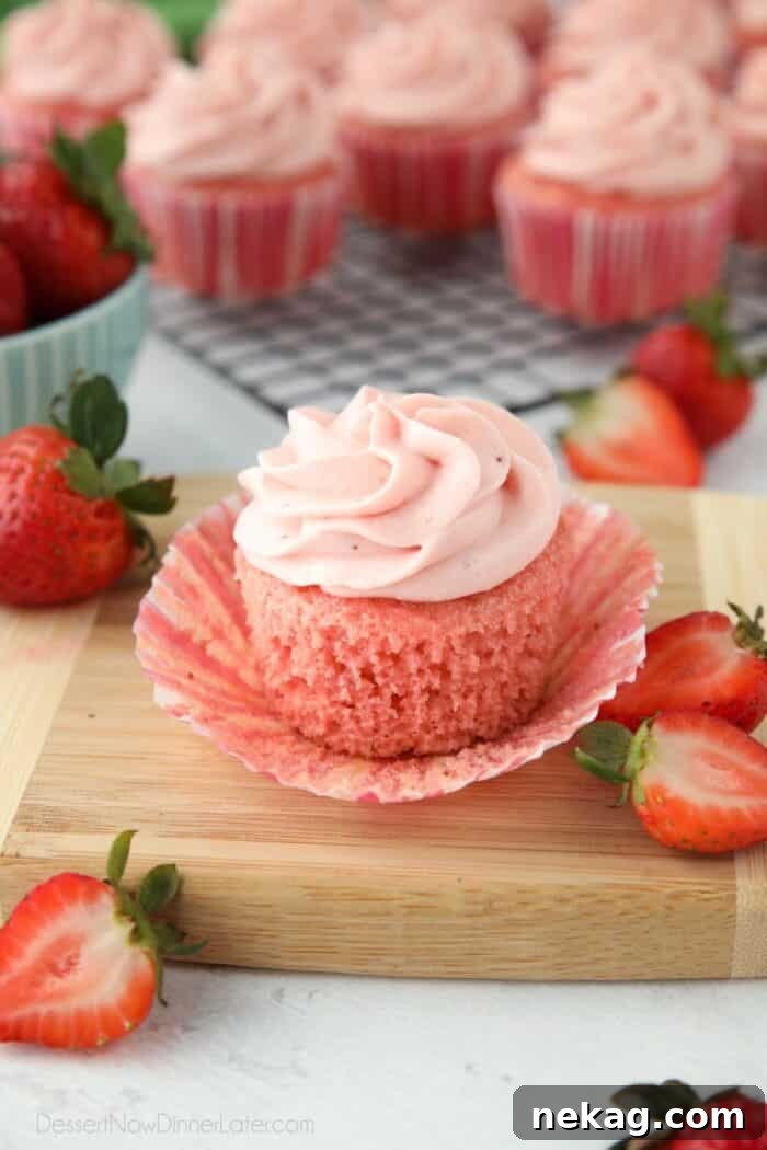 Side view of a strawberry cupcake with the wrapper pulled down to show the texture of the cake.