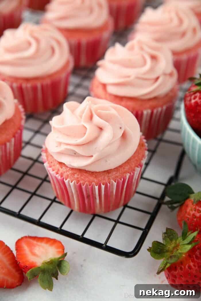 Frosted strawberry cupcakes on a wire cooling rack.