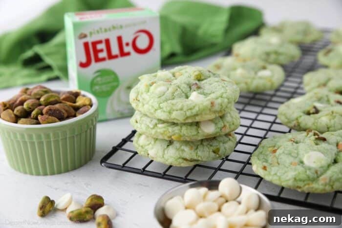 Pudding-Infused Pistachio Delights 9 A stack of pistachio pudding cookies on a cooling rack, with an instant pudding box, shelled pistachios, and white chocolate chips artfully arranged nearby, highlighting the key ingredients.