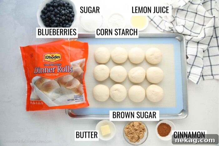 Gooey Blueberry Cinnamon Swirls 7 A flat lay photograph displaying all the key ingredients for blueberry cinnamon rolls: a bowl of fresh blueberries, granulated sugar, corn starch, a lemon, Rhodes dinner rolls, softened butter, brown sugar, and ground cinnamon.