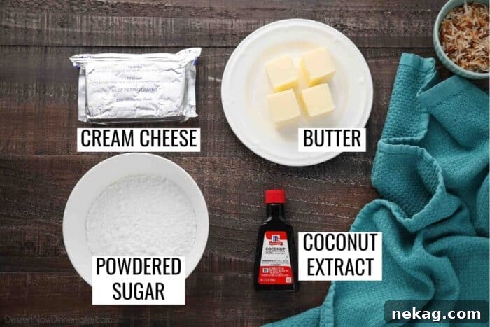 The four essential ingredients for Coconut Cream Cheese Frosting laid out: a block of cream cheese, a stick of butter, a bowl of powdered sugar, and a bottle of coconut extract.