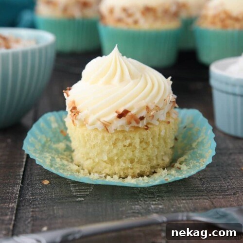 Close-up side view of a coconut cupcake with the paper wrapper pulled down.