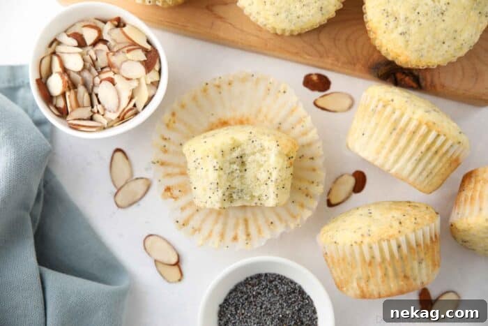 Golden Almond Poppy Seed Muffins 9 A bite taken out of a muffin, revealing the moist cake texture and the distribution of poppy seeds.
