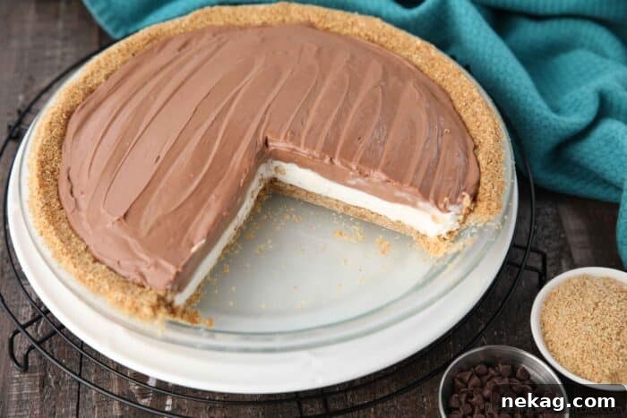 A close-up shot of the assembled no-bake cheesecake pie, resting in its graham cracker crust, showcasing the smooth, dual-layered filling before chilling.