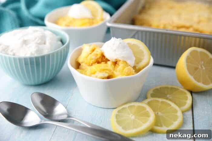 Effortless Lemon Sunshine Cake 8 A close-up of a serving of Lemon Dump Cake in a bowl, showing the warm, gooey layers of lemon filling and melted cream cheese beneath the golden cake topping. It looks incredibly appetizing.