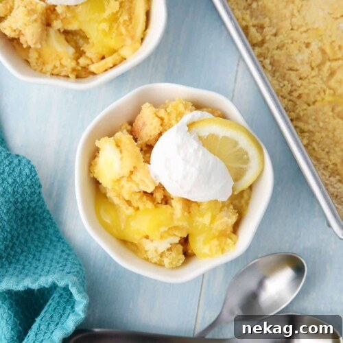 Effortless Lemon Sunshine Cake 9 Lemon Dump Cake in a small bowl topped with whipped topping and a lemon slice.