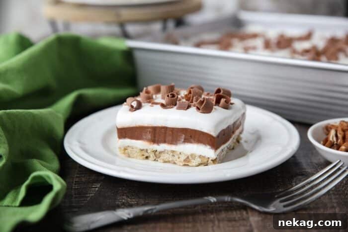 Layered Chocolate Delight dessert with a pecan crust, cream cheese, chocolate pudding, and whipped topping, garnished with chocolate curls.