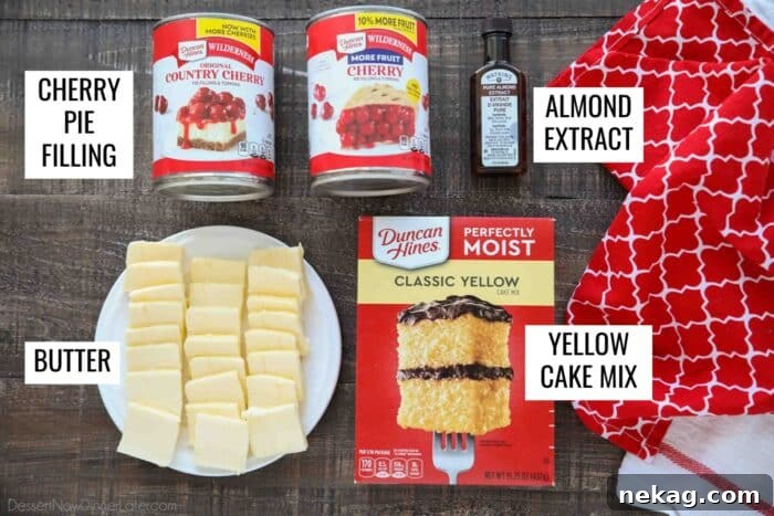 All four essential ingredients for Cherry Dump Cake laid out: two cans of cherry pie filling, a bottle of almond extract, a box of yellow cake mix, and sticks of butter.