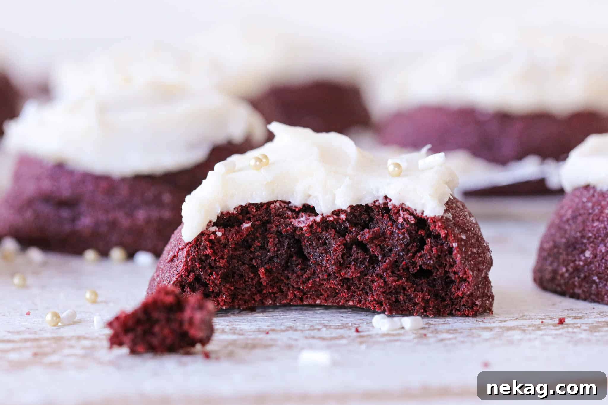 A red velvet cookie's interior crumb, revealing its soft texture, topped with creamy white frosting.