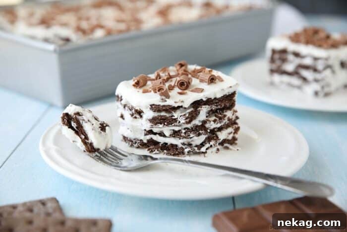 A close-up view of a beautifully prepared Icebox Cake, featuring clear layers of chocolate graham crackers and whipped cream, crowned with decorative chocolate curls.