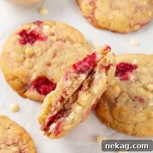 A white chocolate raspberry cookie, broken in half to reveal its appealing chewy texture and generous chocolate chips.