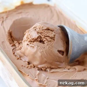 A perfect scoop of chocolate ice cream being served from a frozen glass dish.