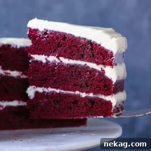 A beautiful slice of Red Velvet Layer Cake with Cream Cheese Buttercream on a cake server.
