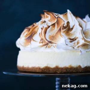 Lemon Meringue Cheesecake displayed on a vintage glass cake stand.
