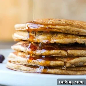 Whole wheat pancakes generously stacked and drizzled with maple syrup.