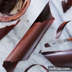 Perfectly tempered dark chocolate ribbons showcased on a marble surface.