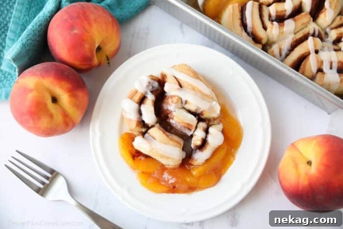 A close-up shot of a single serving of Cinnamon Roll Peach Cobbler on a plate, showing the texture of the baked cinnamon roll and the juicy peach filling.