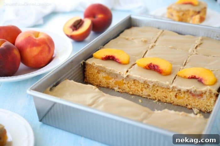 A baked and frosted peach cake inside of a baking pan with sliced peaches on top.