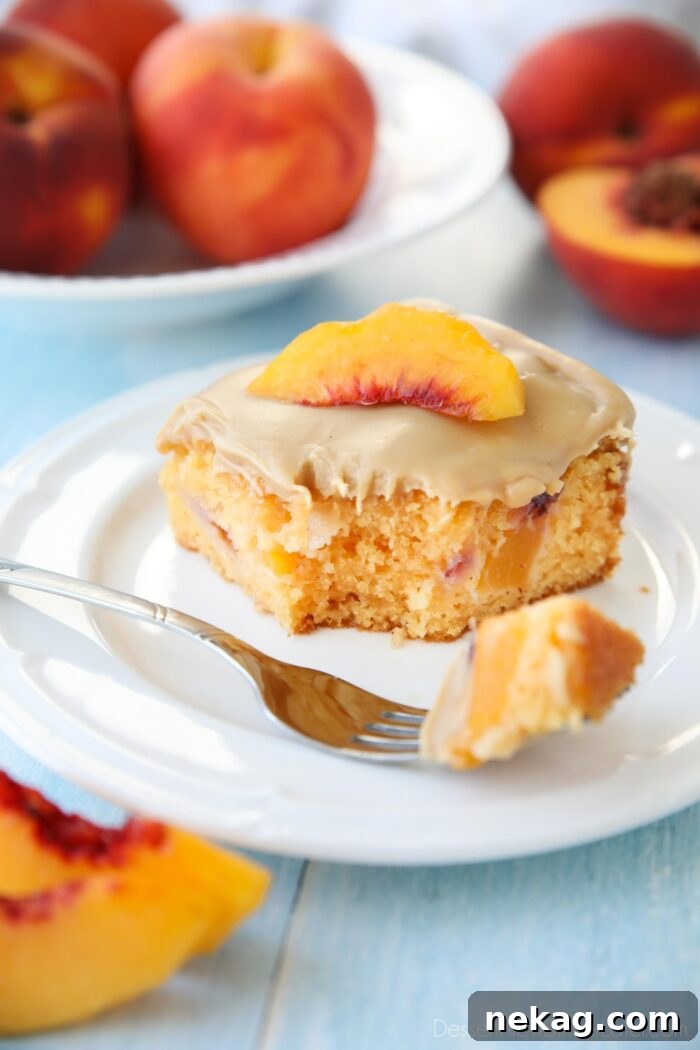 Fork full of peach cake with brown sugar frosting taken out of a slice on a plate.
