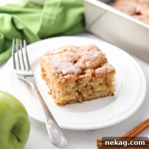 A square piece of glazed apple fritter cake on a plate, ready to be enjoyed.