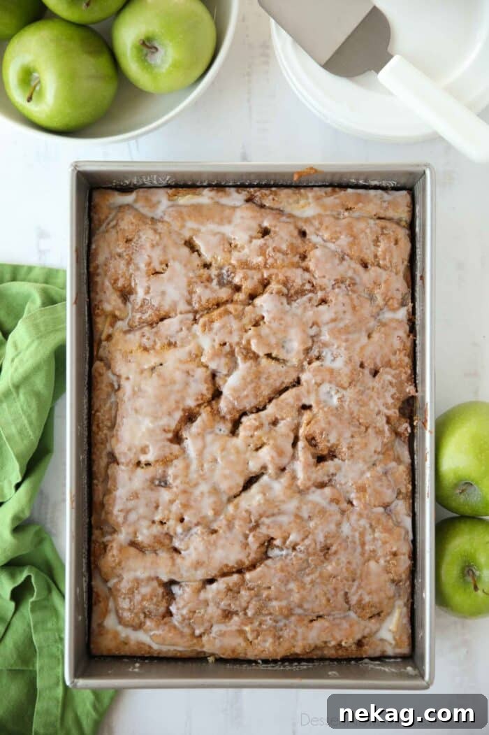 Cinnamon Apple Fritter Cake 3 A glistening, glazed apple fritter cake cooling in a 9x13-inch baking pan, ready to be sliced and served.