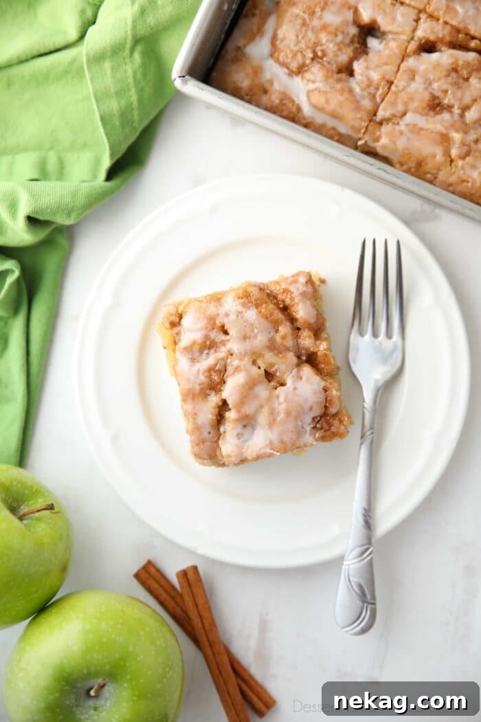 Cinnamon Apple Fritter Cake 4 A top-down view of a glazed apple cinnamon cake on a plate, showing the rich glaze and a peek of the apple filling within.