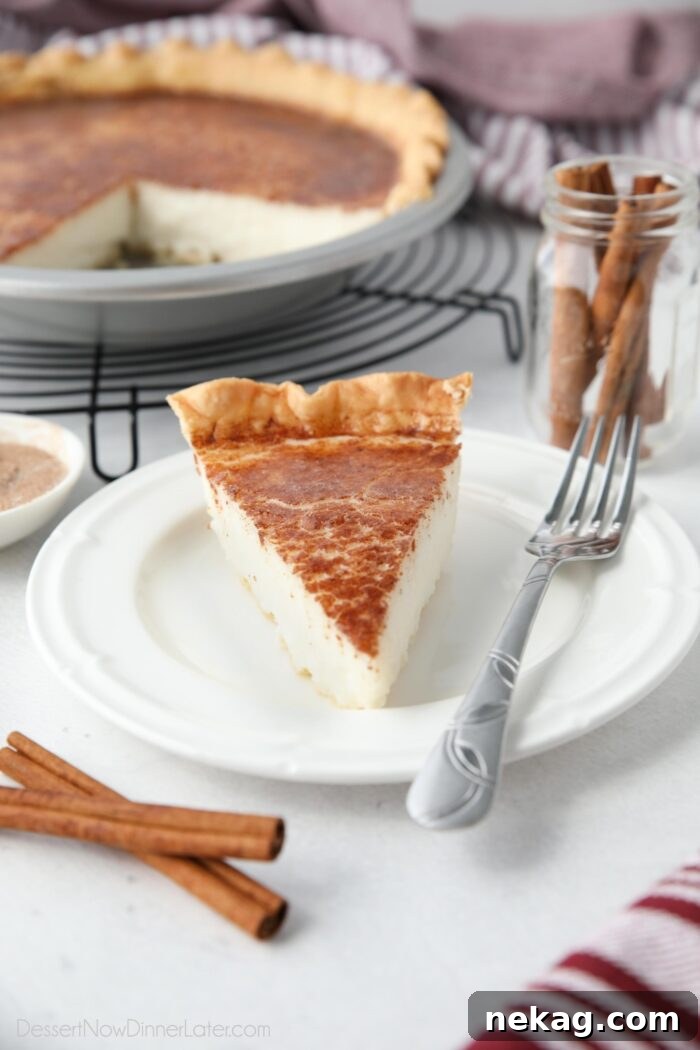 Homemade Sugar Cream Pie Recipe Video 4 A generous slice of Hoosier Pie, artfully presented on a plate, highlighting its smooth vanilla filling and a dusting of cinnamon and nutmeg.