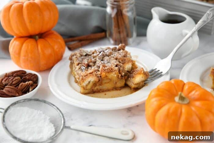 Fall Favorite Pumpkin French Toast Bake 11 A fork lifts a bite from a slice of pumpkin French toast casserole, highlighting its soft interior and streusel topping.