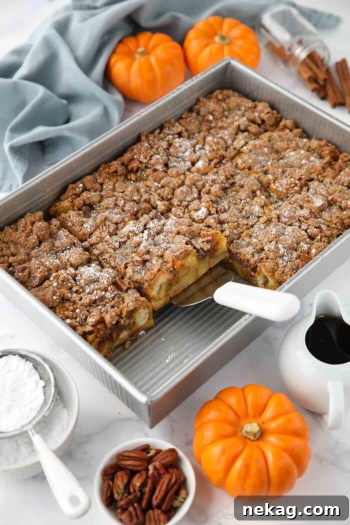 Fall Favorite Pumpkin French Toast Bake 3 A baking pan filled with golden-brown Pumpkin French Toast Casserole, with a serving spatula poised to dish out a portion.