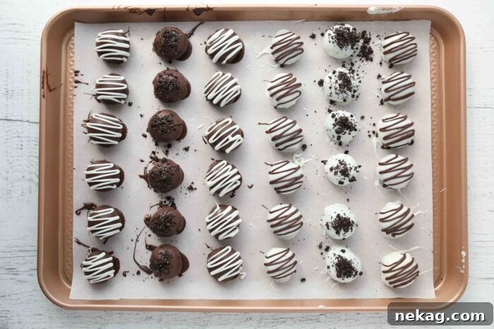 No Bake Oreo Truffles 10 Chocolate dipped Oreo Balls arranged neatly on parchment paper, some with additional crushed cookie topping.