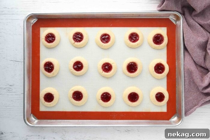 How to Make Raspberry Thumbprint Cookies 9 Baked raspberry thumbprint cookies on a tray.