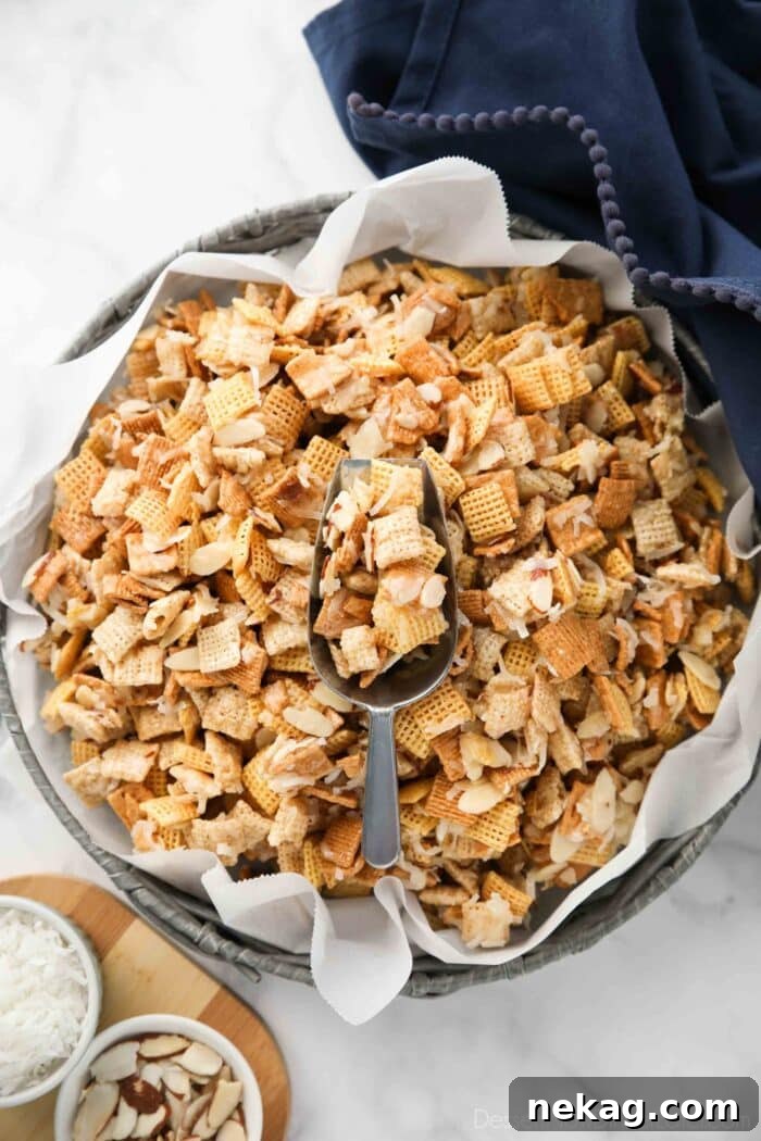Sweet Chex Mix with a serving scoop, showcasing its gooey texture.