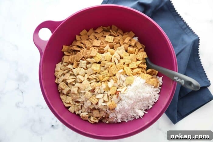 A large bowl containing a mixture of Rice Chex, Corn Chex, Golden Grahams cereals, sliced almonds, and sweetened coconut flakes, ready for coating.