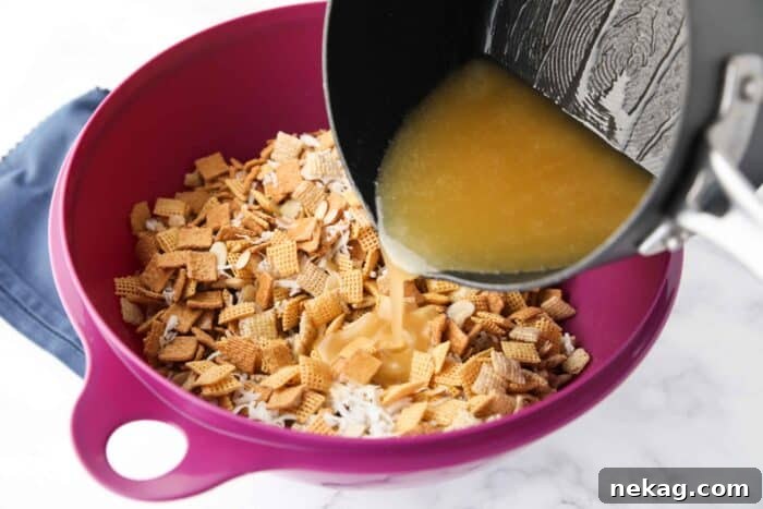 Warm butter and sugar syrup being poured over the cereal mixture in a large bowl, ready for coating.