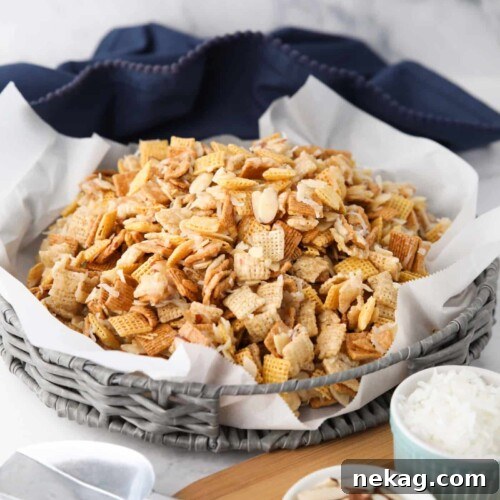 Sweet Chex Mix with coconut and almonds in a large basket lined with parchment paper.