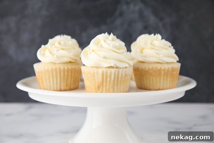 Perfectly Fluffy White Cupcakes 9 Decorated white cupcakes with elegant frosting and sprinkles, artfully arranged on a cake stand.