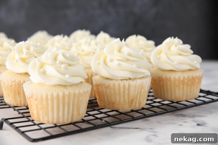 Perfectly Fluffy White Cupcakes 10 Decorated white cupcakes resting on a wire rack, adorned with beautiful frosting and ready to be served.