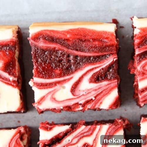 Squares of red velvet brownies with cheesecake swirled on top.