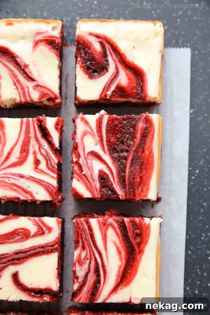 Freshly cut squares of swirled red velvet cheesecake brownies arranged appealingly.