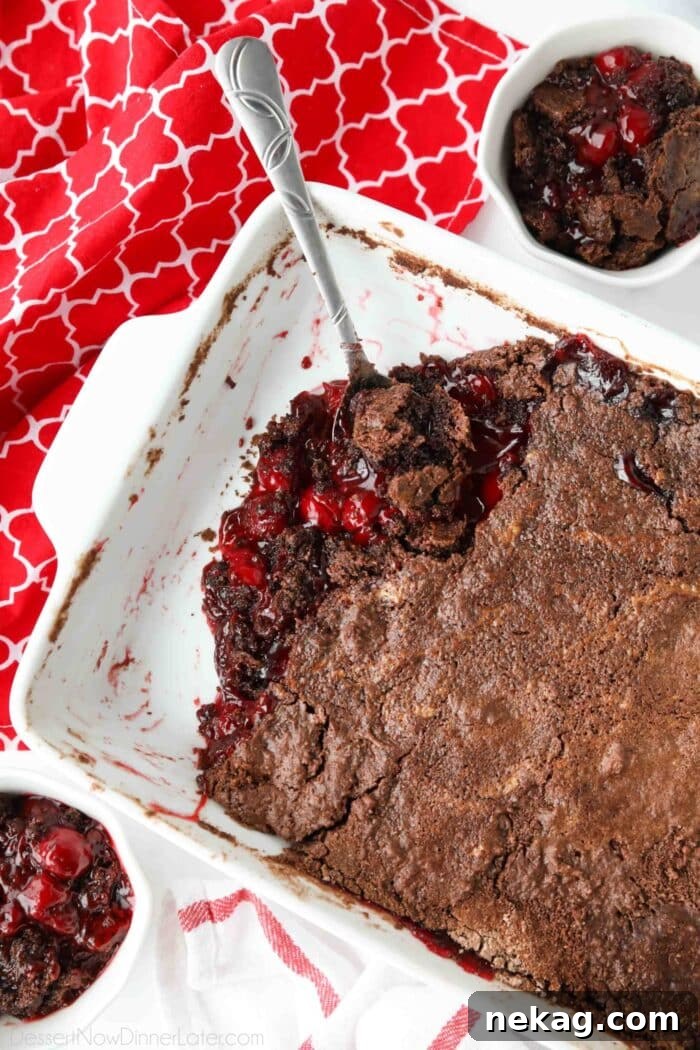 Baked chocolate cherry dump cake in baking dish with a serving spoon.