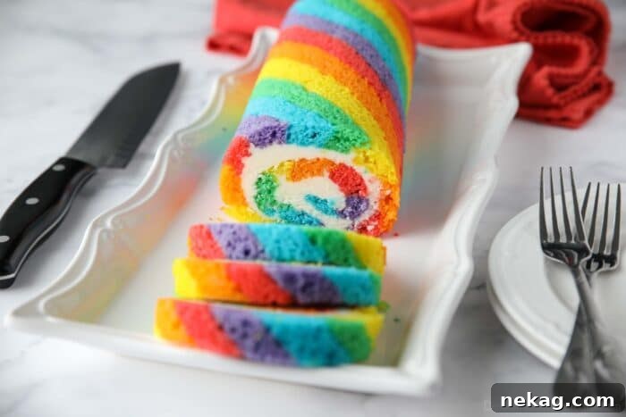 Rainbow Cake Roll with colored cake stripes and vanilla buttercream filling.