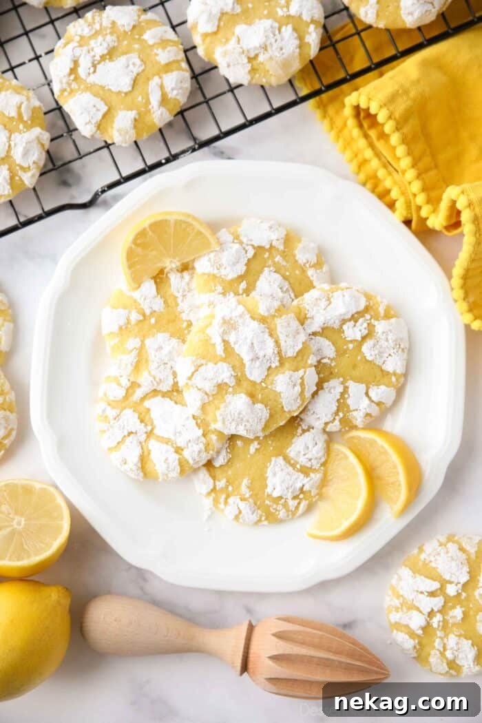Lemon crinkle cookies on a plate with lemon wedges.