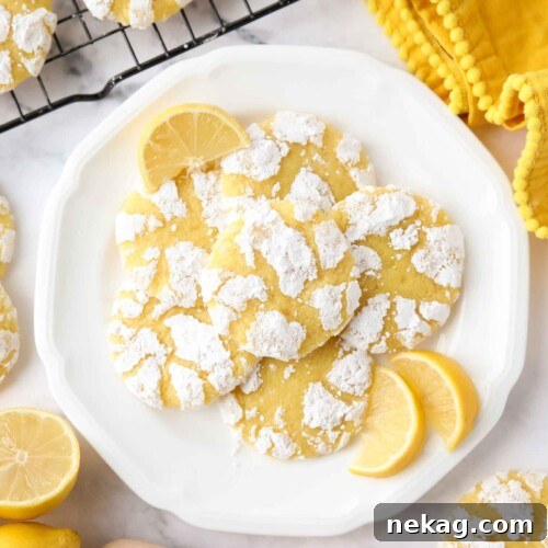 Lemon crinkle cookies on a plate with lemon wedges.