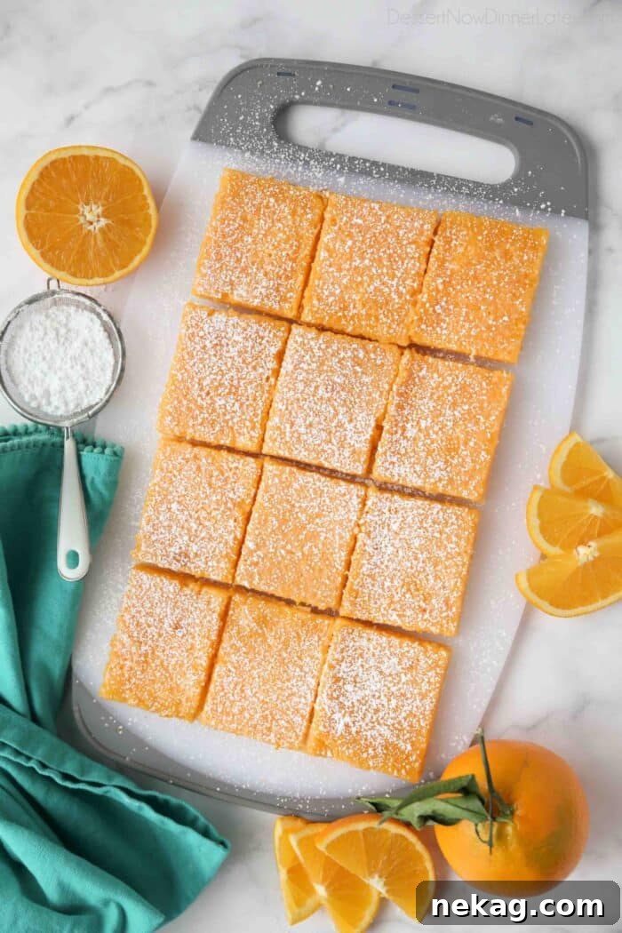 Golden Citrus Bars 4 An overhead view of freshly baked orange bars, perfectly cut into uniform squares, arranged on a rustic wooden board.
