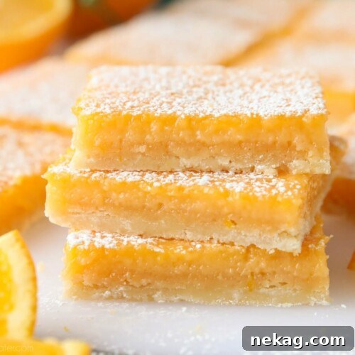 Close-up of a stack of orange bars with powdered sugar dusted on top, highlighting their texture.