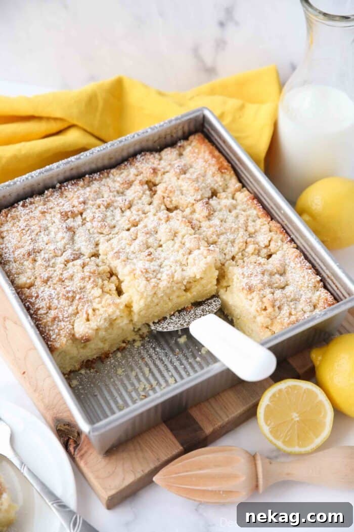 Zesty Lemon Coffee Cake 3 A freshly baked Lemon Coffee Cake with a generous crumb topping, lightly dusted with powdered sugar, sitting in a square baking pan.