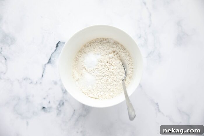 Dry ingredients including flour, baking soda, and salt, neatly arranged in a bowl with a spoon, ready for mixing.