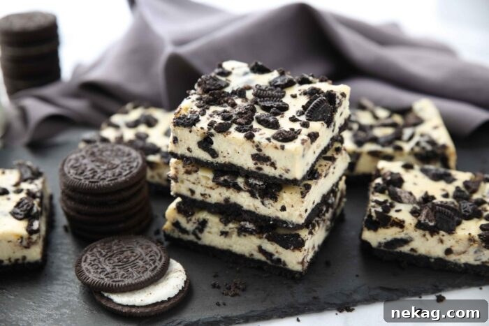 Oreo Crunch Cheesecake Bars 9 A vibrant display of three stacked Oreo cheesecake bars alongside more bars and loose Oreos.