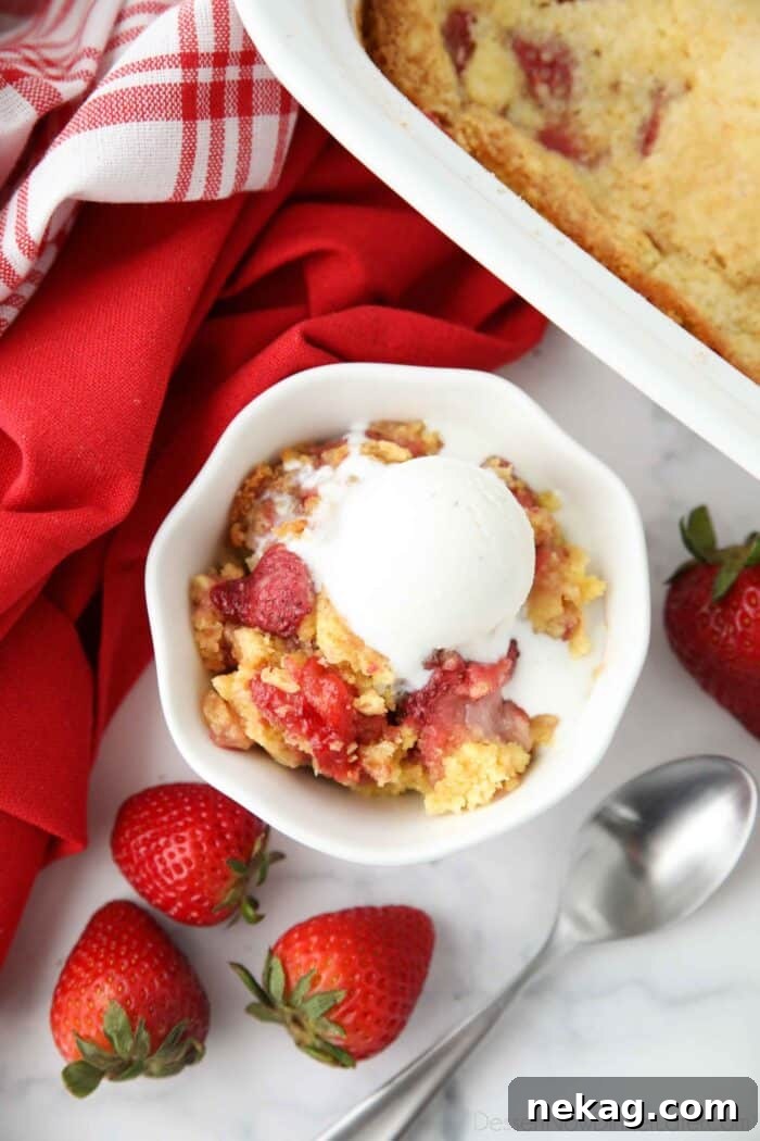 Effortless Strawberry Delight 2 A serving of homemade Strawberry Dump Cake, topped with a scoop of vanilla ice cream, presented in a clear glass bowl.