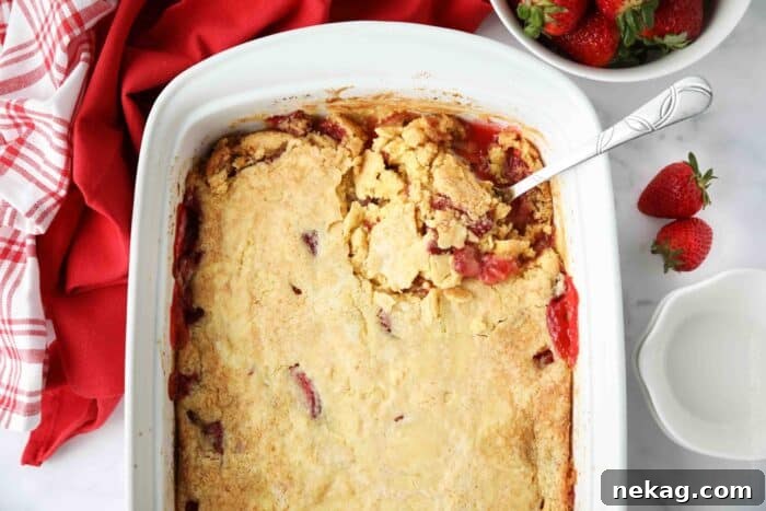 Effortless Strawberry Delight 7 A close-up shot of a baked Strawberry Dump Cake in a pan, showcasing its bubbling fruit filling and golden-brown, crispy cake topping.
